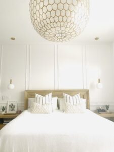 white bed with decorative pillows and large gold and white lamp