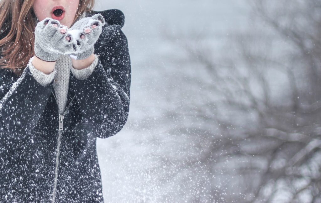 thumbnail woman blowing snow from her gloves