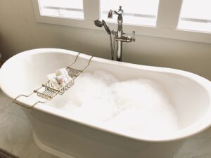 white bathtub with wire rack full of bath products