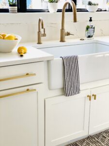 closeup of white sink with gold handles and black and white towel