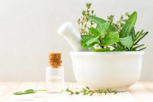 mortar and pestle with green plants and glass bottle with cork stopper