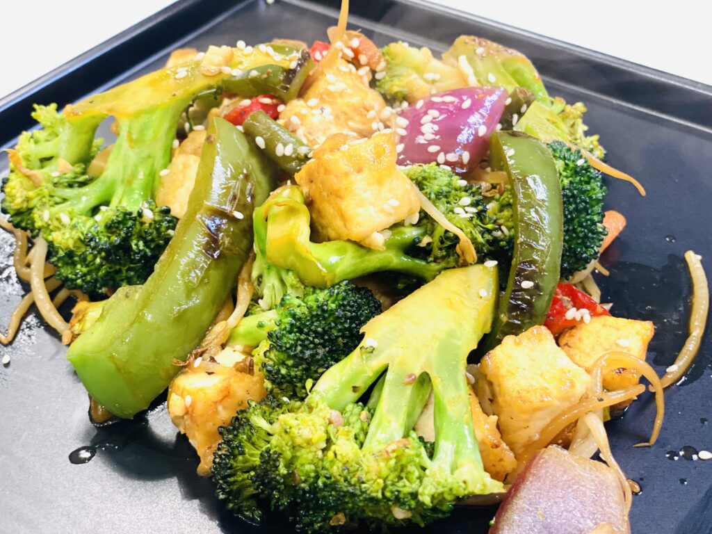 black tray with roasted vegetables and sesame seeds