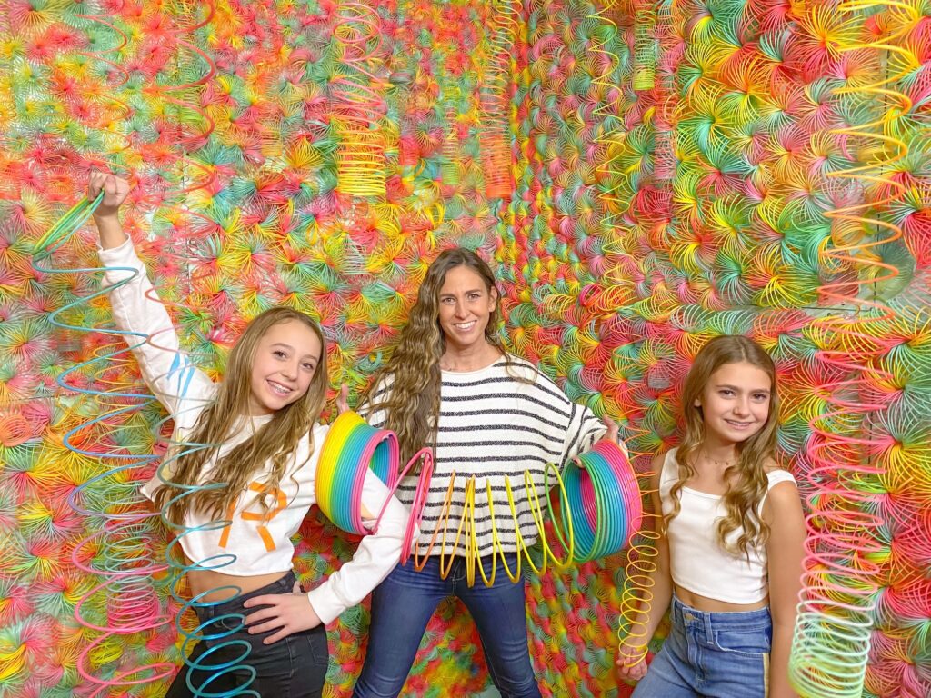 Three girls in a rainbow room with large rainbow springs