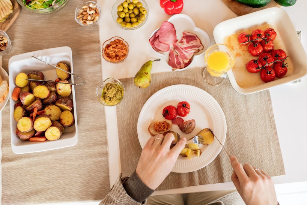 Table full of tomatoes, ham, potatoes, and other delicious food